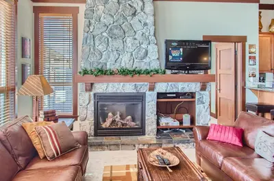 a living room with couches and a stone fireplace at Stonegate Resort Unit A402 in Big White
