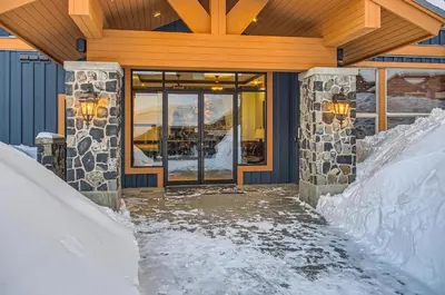 a snow covered entrance to a building with a glass door at Stonegate Resort Unit A402 in Big White