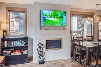 a living room with a fireplace and a television on a wall at Stonegate Resort Unit B108 in Big White