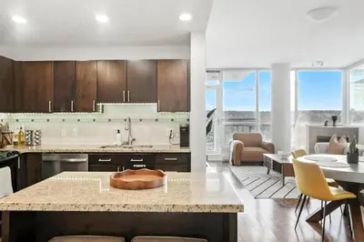 a kitchen and living room with a table and chairs at Elevated Elegance in Calgary