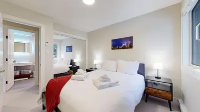 a bedroom with a large white bed and a bathroom at TELEMARK 25 Ski-In Ski-Out Access Steps To Ski Lifts Renovated Townhome in Whistler