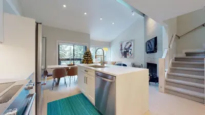a kitchen and living room with a staircase and a table at TELEMARK 25 Ski-In Ski-Out Access Steps To Ski Lifts Renovated Townhome in Whistler