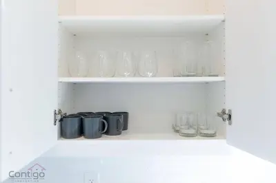 a cupboard with glasses and other glass items on it at Jungle House, AirCon, Sleeps 8, Near WEM & DT! in Edmonton