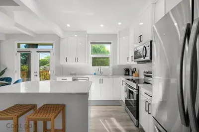 a white kitchen with white cabinets and a refrigerator at Urban Jungle Getaway, AirCon, 10min to DT & WEM! in Edmonton
