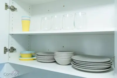 a white shelf with plates and bowls and glasses at The Den, Centrally Located Suite, King Bed, WiFi! in Edmonton