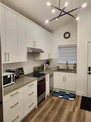 a kitchen with white cabinets and a clock on the wall at 2BR Detached Guesthouse - Free Parking -10 mins to YVR & Downtown in Vancouver