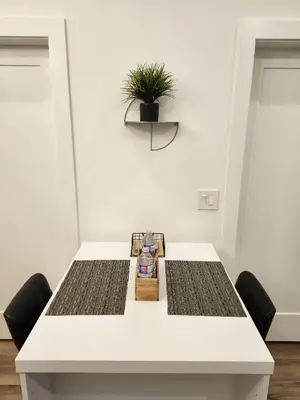 a white table with two chairs and a potted plant at 2BR Detached Guesthouse - Free Parking -10 mins to YVR & Downtown in Vancouver