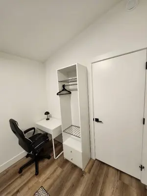 a room with a chair and a desk and a closet at 2BR Detached Guesthouse - Free Parking -10 mins to YVR & Downtown in Vancouver
