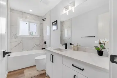 a white bathroom with a tub and a toilet and a sink at Your stay at Haysboro in Calgary