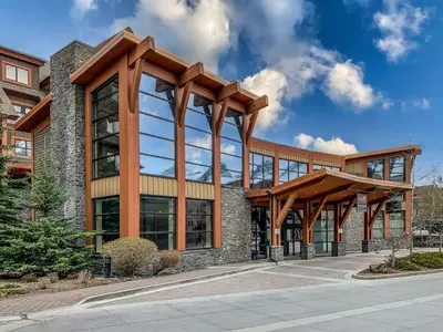a large building with glass windows and a wooden roof at Luxury Rockies Retreat 1BR with Views in Canmore