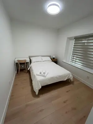a white bedroom with a bed and a window at Waverley Guest Room in Vancouver in Vancouver