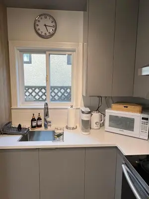 a kitchen with a sink and a clock on a window at Waverley Guest Room in Vancouver in Vancouver