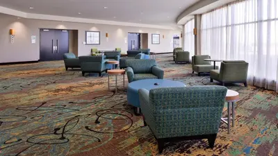 a waiting room with chairs and tables and windows at Holiday Inn Hotel & Suites Edmonton Airport Conference Centre by IHG in Nisku