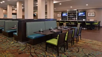 a restaurant with tables and chairs and a bar at Holiday Inn Hotel & Suites Edmonton Airport Conference Centre by IHG in Nisku