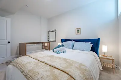 a bedroom with a large bed with blue pillows at Luxe Suite close to Spruce Meadows in Priddis