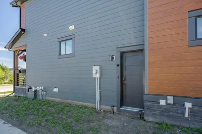 a gray house with a door and a parking meter at Luxe Suite close to Spruce Meadows in Priddis