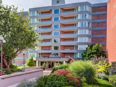 an apartment building with a garden in front of it at Coastal Charm - min 3-Day Stay Breathtaking Views with Work Desk by Victoria Prime! in Victoria