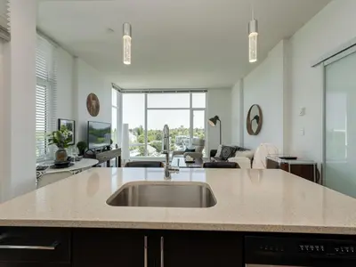 a kitchen with a sink and a living room at The Bohemian, min 30-Day Stay with Breathtaking Views and Home Office by Victoria Prime! in Victoria