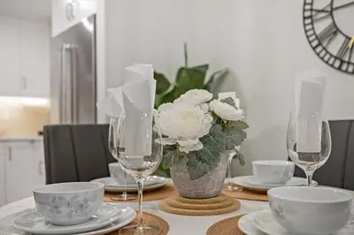 a table with two wine glasses and a vase of flowers at Le Bucheron Stunning Spring Creek Luxury condo in Canmore