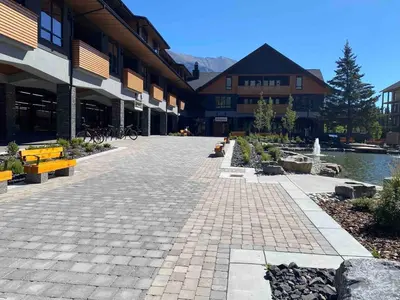 a courtyard of a building with benches and a lake at Le Bucheron Stunning Spring Creek Luxury condo in Canmore