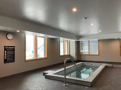 a hot tub in a room with a clock and windows at Le Bucheron Stunning Spring Creek Luxury condo in Canmore