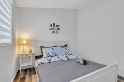 a white bedroom with a bed and a night stand at ModernOasis with AC&MovieRoom close to Downtown15' Banff 60' in Calgary