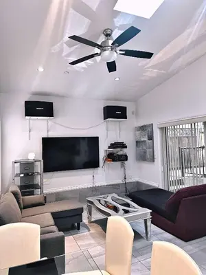 a living room with a ceiling fan and a flat screen tv at The warm and lovely coach home in Vancouver