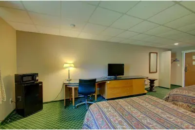 a hotel room with two beds and a desk with a computer at Victorian Motel & RV Park by Capital O in Grand Forks