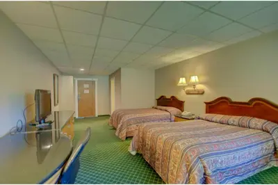 a hotel room with two beds and a flat screen tv at Victorian Motel & RV Park by Capital O in Grand Forks