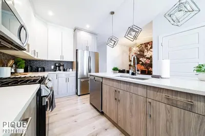 a kitchen with white cabinets and a stainless steel refrigerator at Modern Retreat - 3 King Beds - Garage - WiFi - Sleeps 10 in Edmonton
