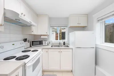 a white kitchen with a stove and a sink at Cozy and Modern 2br guesthouse in Vancouver