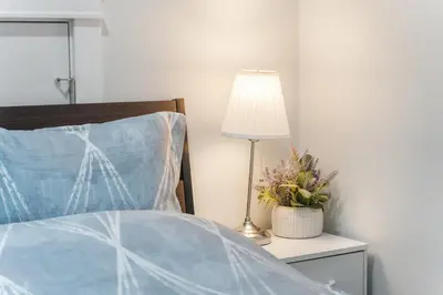 a bed with a blue comforter and a lamp on a table at Cozy and Modern 2br guesthouse in Vancouver