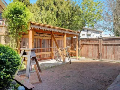 a wooden shed with a bike parked next to a fence at Fairfield Estate Coach House - 30-Day Stay, steps from Cook Street Village by Victoria Prime! in Victoria