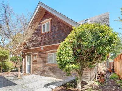 a wooden house with a tree in front of it at Fairfield Estate Coach House - 30-Day Stay, steps from Cook Street Village by Victoria Prime! in Victoria