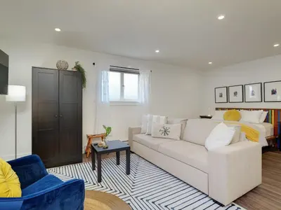 a living room with a white couch and a bed at Fairfield Estate Coach House - 30-Day Stay, steps from Cook Street Village by Victoria Prime! in Victoria