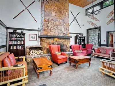 a living room with red chairs and a stone fireplace at Powder & Pines Boutique Apartment in Whistler