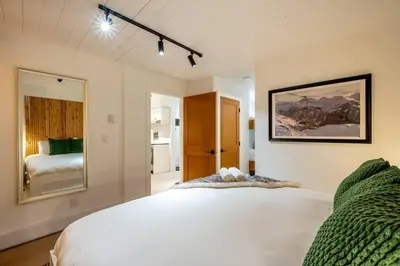 a bedroom with a white bed and a mirror at Powder & Pines Boutique Apartment in Whistler