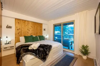 a bedroom with a large bed and a window at Powder & Pines Boutique Apartment in Whistler