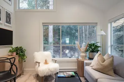 a living room with a couch and a window at Skywood-Designer Condo,Steps to Creekside Gondola, Free Parking in Whistler
