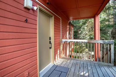 a red house with a deck with a door at Skywood-Designer Condo,Steps to Creekside Gondola, Free Parking in Whistler