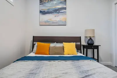 a bedroom with a bed with yellow and blue pillows at Perfect Stay 2 Bedroom Basement Suite in Airdrie