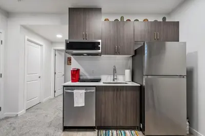 a kitchen with a stainless steel refrigerator and cabinets at Perfect Stay 2 Bedroom Basement Suite in Airdrie