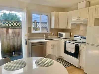 a kitchen with white appliances and a table with chairs at Entire 1Bed 1Bath Suite Coquitlam Centre in Port Coquitlam