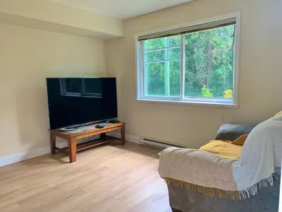 a living room with a flat screen tv and a couch at Entire 1Bed 1Bath Suite Coquitlam Centre in Port Coquitlam