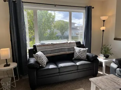 a living room with a couch and a large window at 4br Crew House - Big, Bright, Modern, Fully Stocked in Grande Prairie