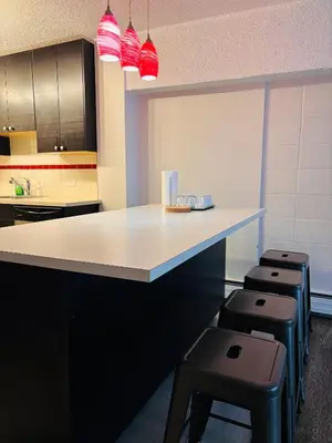 a kitchen with a white counter and stools at 5th Floor 1 Bedroom Condo with Parking in Calgary