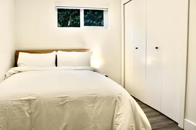 a white bedroom with a bed and a window at 2BDR Stylish Comfort Parkside in Vancouver