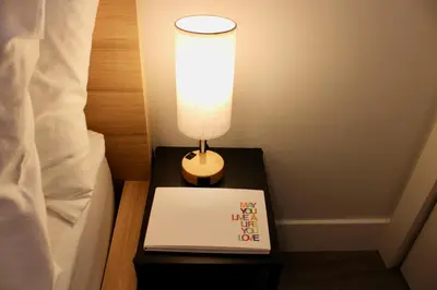 a lamp on a table next to a bed with a book at 2BDR Stylish Comfort Parkside in Vancouver