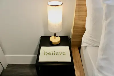 a lamp on a black table next to a bed at 2BDR Stylish Comfort Parkside in Vancouver