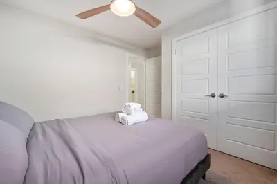 a white bedroom with a bed with a ceiling fan at 3 Bedroom Sage House with AC, Driveway Parking, King Bed & More in Calgary